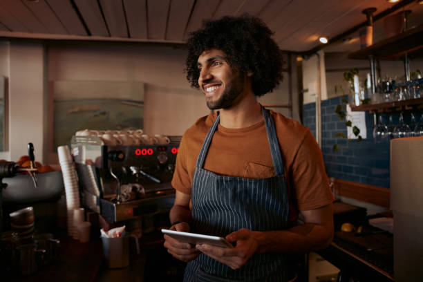 istock Successful small male business owner wearing apron using digital tablet and looking away 1288597917