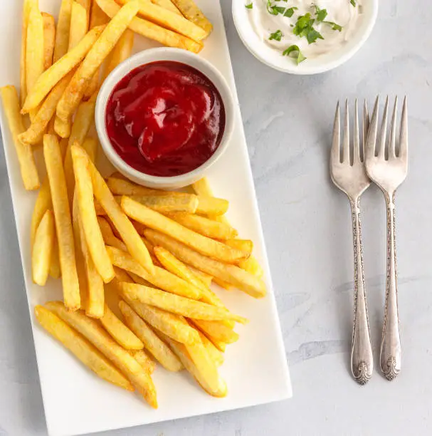 French Fries  on a Platter with Tomato Ketchup and Mayonnaise Directly Above Horizontal Photo on White Background