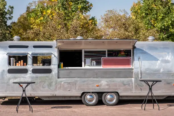 Photo of Classic chrome food wagon in park. Food truck.