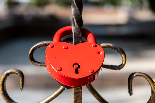 Heart shaped padlock chained to a railing of bridge. Red padlock for lovers.