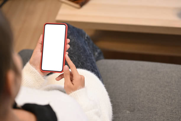 istock Cropped shot of young woman using mobile phone sending sms or texting while sitting on couch at home. 1288602436