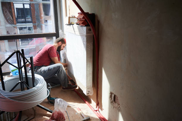 istock Male worker installing radiator in a new empty room next to the window 1288603222