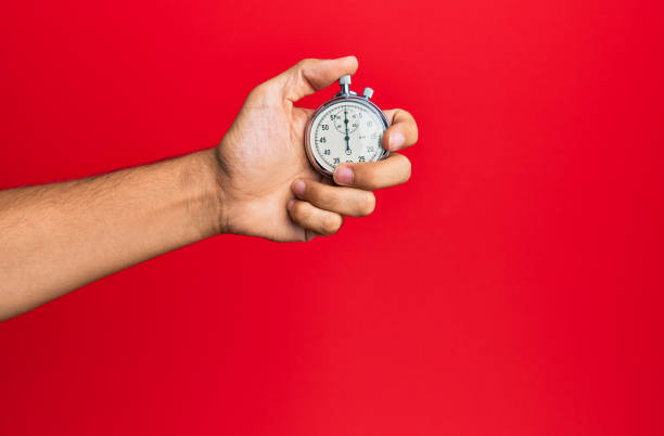 istock Hand of young hispanic man using stopwatch over isolated red background. 1288604027