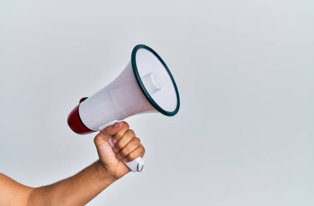 istock Hand of hispanic man holding megaphone over isolated white background. 1288604057