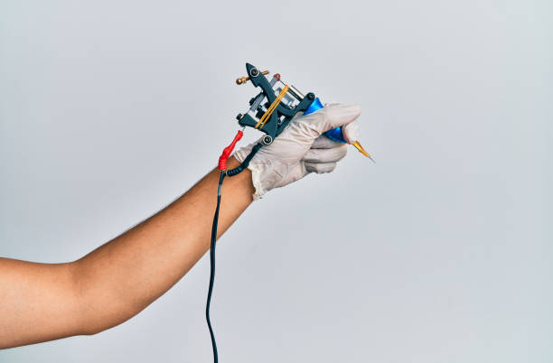 Hand of young hispanic man using tattoo machine over isolated white background. Hand of young hispanic man using tattoo machine over isolated white background. tattooing stock pictures, royalty-free photos & images