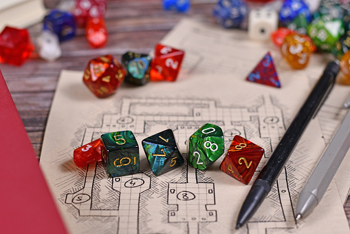 Colorful tabletop role playing RPG game dices on blurry hand drawn dungeon map with other dices in background
