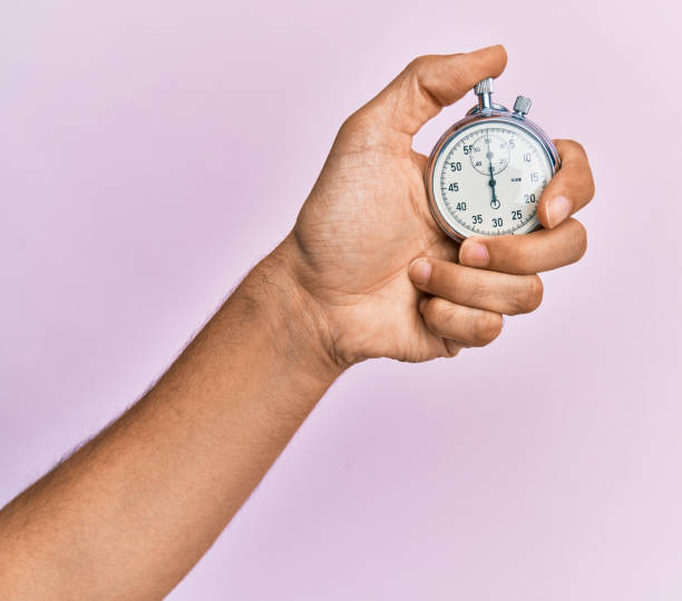 istock Hand of young hispanic man using stopwatch over isolated pink background. 1288605151