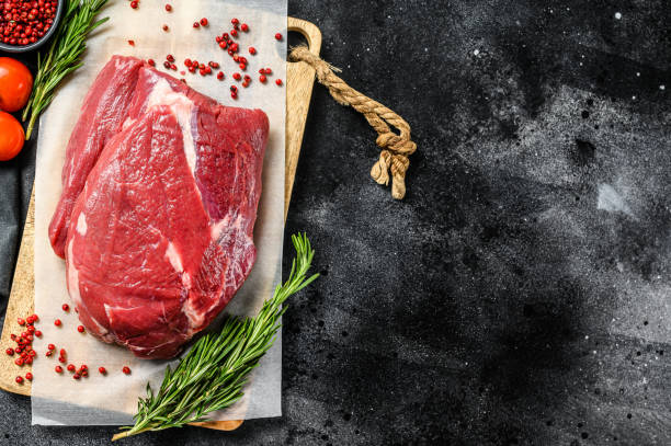 istock Raw Round beef cut on a cutting board. Black background. Top view. Copy space 1288605567