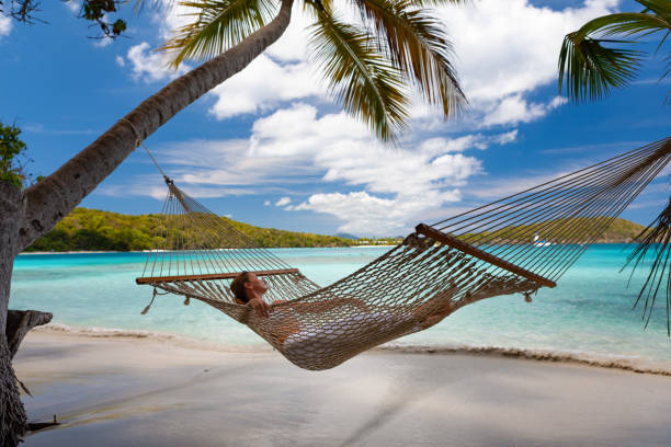 istock Woman relaxing in a hammock on a pristine tropical beach 1288605579