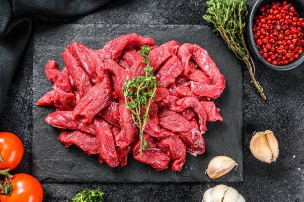 istock Raw beef Stroganoff meat. Black background. Top view 1288606419