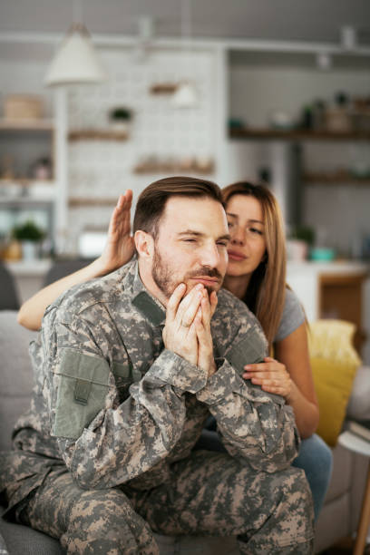istock Depressed soldier sitting on sofa in living room. 1288607165