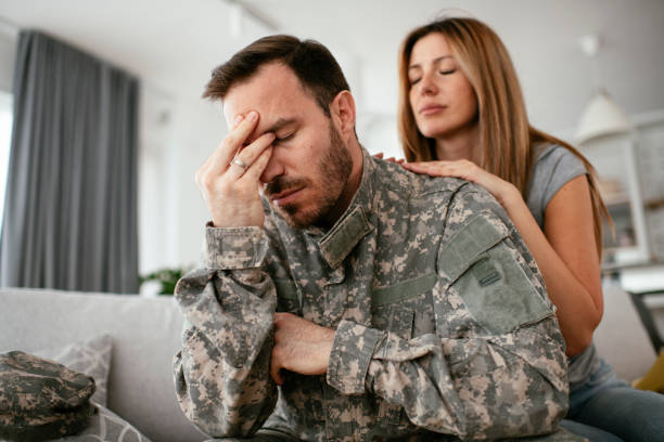 soldato depresso seduto sul divano in salotto. - men male military beautiful foto e immagini stock