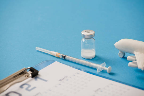 istock Vaccine with syringe, calendar 2021, and white plane, blue background 1288609218