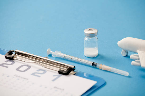 istock Vaccine with syringe, calendar 2021, and white plane, blue background 1288609232
