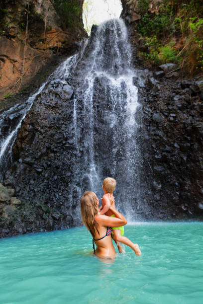 istock Mother with kids stand under  waterfall 1288610233