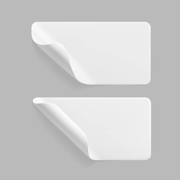 istock White glued rectangle stickers with curled corners mock up set. Blank white adhesive paper or plastic sticker label with wrinkled and creased effect. Template label tags close up. 3d realistic vector 1288610665