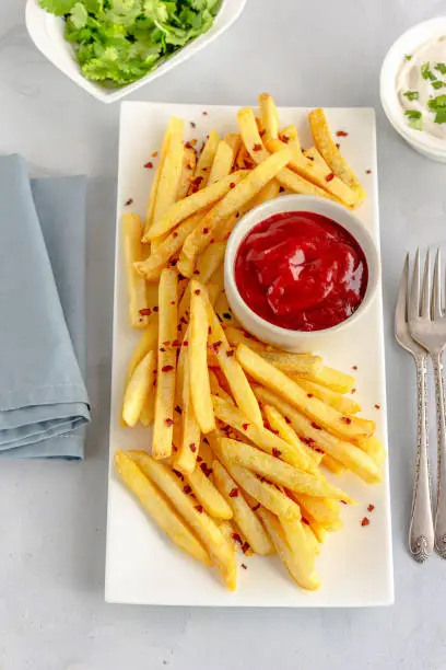 Freshly Fried French Fries on a Plate with Condiments on White Background