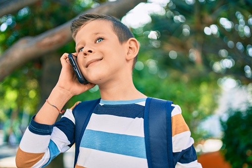 Adorable caucasian student boy smiling happy talking on the smartphone at the park.