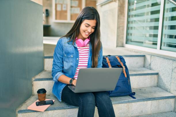 Young hispanic student girl smiling happy using laptop at the university.