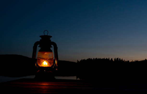 夕方には湖の橋の上に暖かい黄色の光を持つ古い灯油ランタン。 - oil lantern ストックフォトと画像