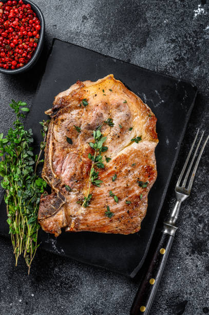 istock Grilled pork loin steak on a marble board. Black background. Top view 1288617826