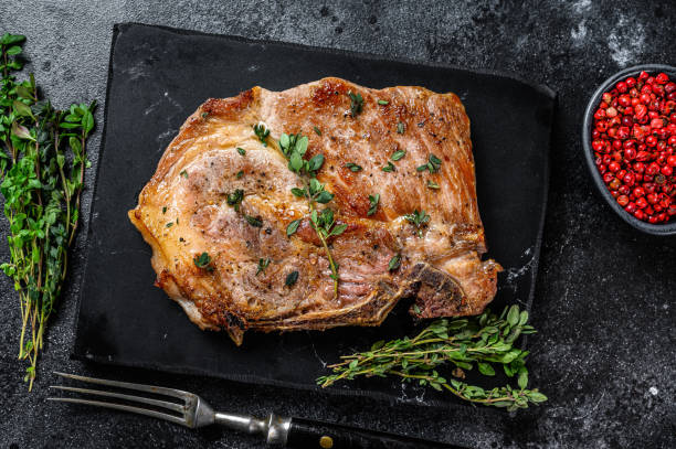 istock Grilled pork loin steak on a marble board. Black background. Top view 1288617850