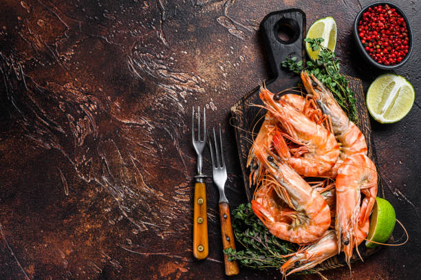 istock Giant Tiger Prawns shrimps on a cutting board with herbs.  Dark background. Top view. Copy space 1288618057
