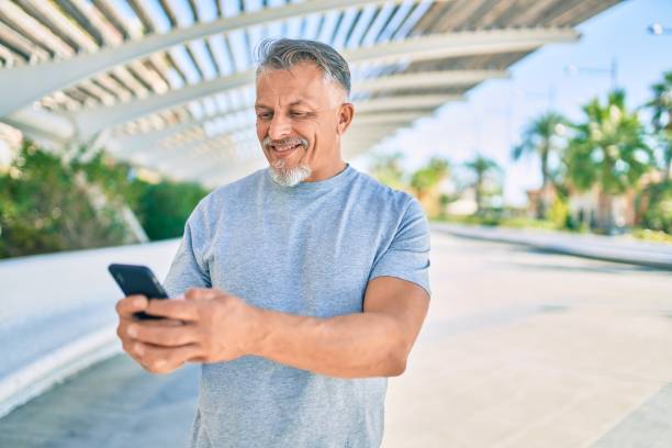 istock Middle age hispanic grey-haired man smiling happy using smartphone at the park. 1288618091