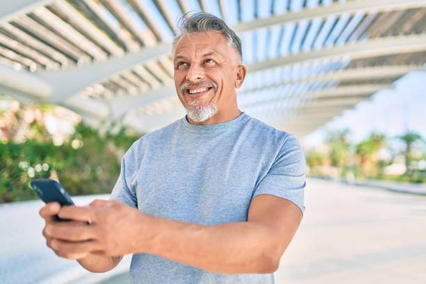 istock Middle age hispanic grey-haired man smiling happy using smartphone at the park. 1288618103