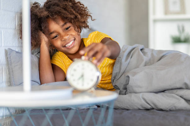 Young girl waking up with alarm clock Young African American girl waking up and smiling in the morning napping photos stock pictures, royalty-free photos & images