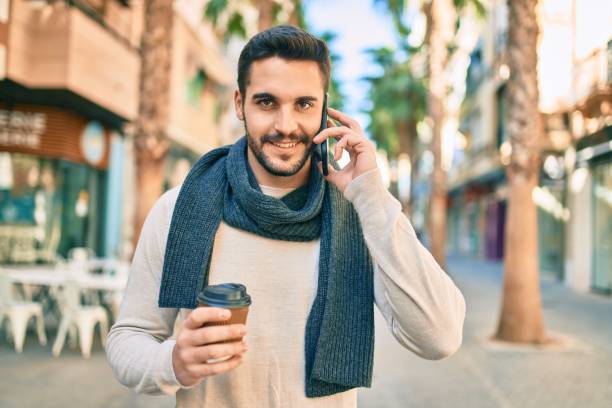 istock Young hispanic man smiling happy talking on the smartphone and drinking take away coffee at the city. 1288618344