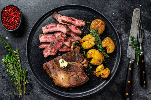 グリルリブアイビーフ肉ステーキをポテトと一緒にカットします。黒の背景。トップビュー - rib eye steak steak beef prepared potato ストックフォトと画像