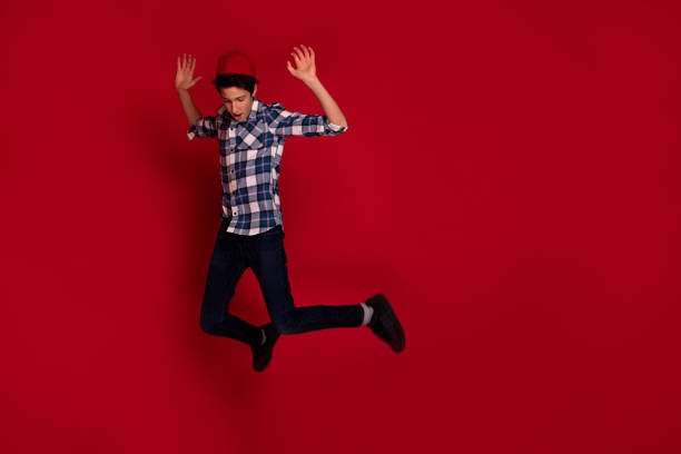 istock Young expressive teenager jumping over red background. 1288618480