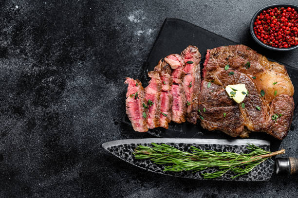 istock Cut Grilled Chuck eye roll beef meat steak on a marble board. Black background. Top view. Copy space 1288618516