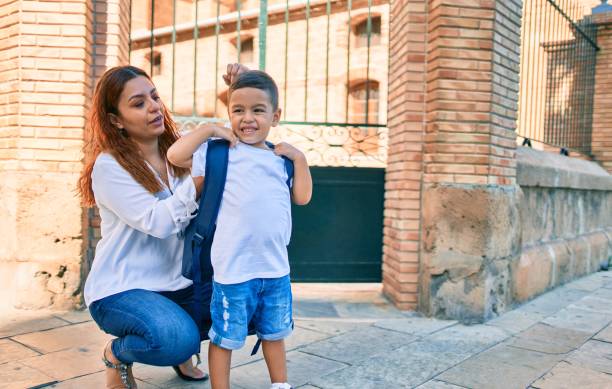 istock Latin mother putting up backpack her student son at the city. 1288621344
