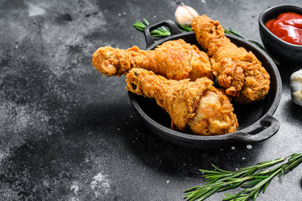 istock Fried crispy chicken legs, drumstick in a pan. Black background. Top view. Copy space 1288622636