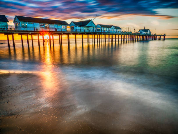 istock Southwold pier at sunrise with waves lapping up sandy beach and sun shining through structure, Southwold, Suffolk, England, Britain 1288623537