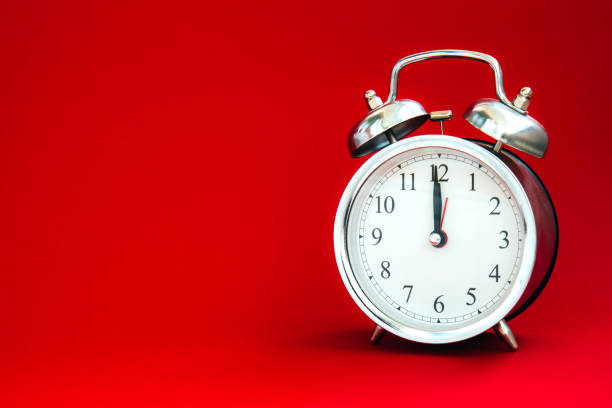 istock Beautiful silver vintage alarm clock on a bright red background 1288623913