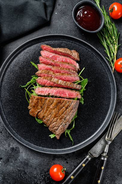 istock Grilled and cut Flat Iron steak. Marble beef meat. Black background. Top view 1288625798