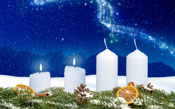 two candles on an advent wreath burns with wintery background and snow