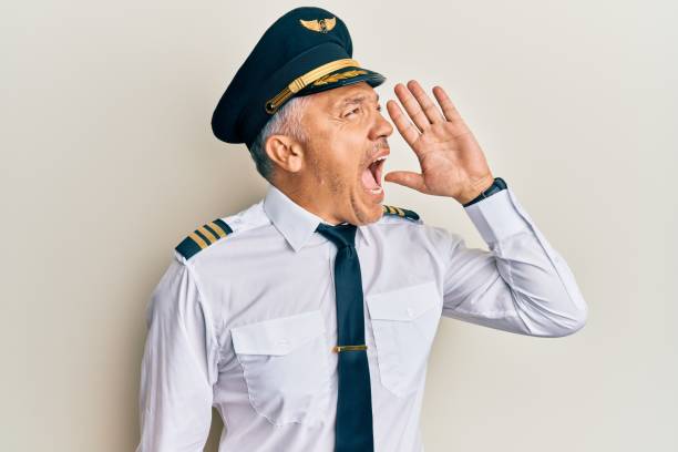 Handsome middle age mature man wearing airplane pilot uniform shouting and screaming loud to side with hand on mouth. communication concept.