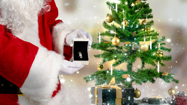 le père noël retient un cas de bijoux avec un anneau dans sa main - christmas santa claus gift holding photos et images de collection
