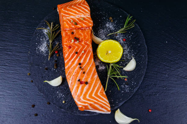 istock Raw salmon fillet with spices on black slate. Top view 1288629632