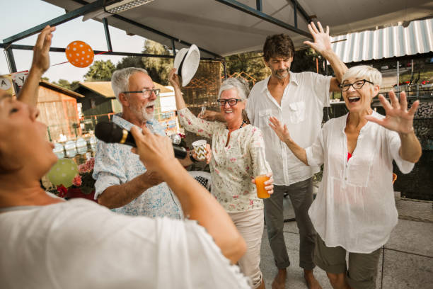 istock Senior people celebrating birthday singing karaoke. 1288631175