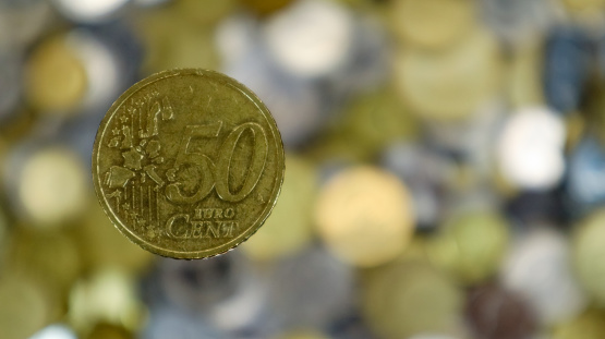 A close-up shows one 50 euro cent coin. This is money. Blurred money background. Eurozone changeable coin worth 0.5 euros. The coin is made from Nordic gold alloy