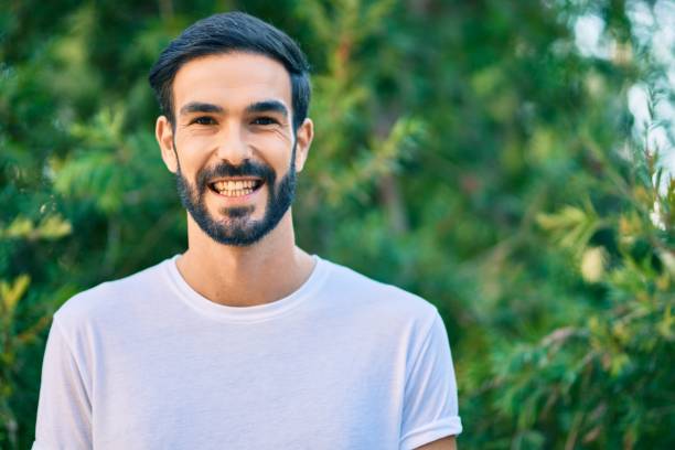 istock Young hispanic man smiling happy standing at the park. 1288632916