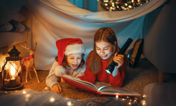 istock sisters reading a book near Christmas tree 1288633417