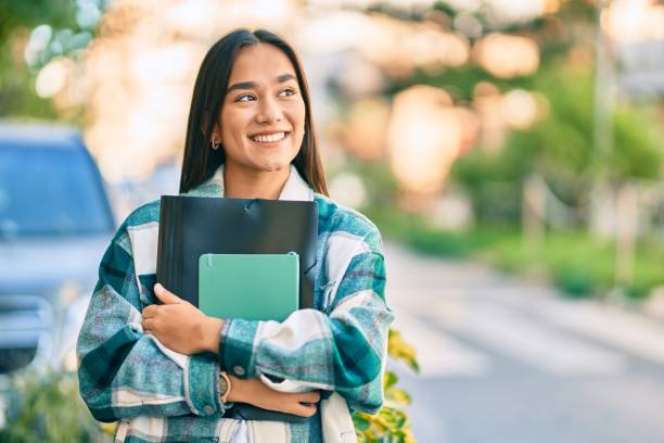 jeune fille latine d’étudiant souriant le dossier heureux de fixation à la ville. - fun walk photos photos et images de collection