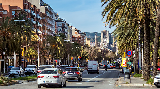 Barcelona, Spain - December 24, 2019: Traffic and people in Carrer de la Marina on a winter day. The Sagrada Familia can be seen in the background.