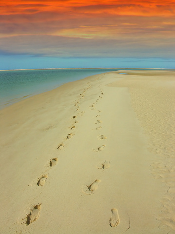 A couple walked on this deserted beach at sunset, their footprints can be seen on the sand